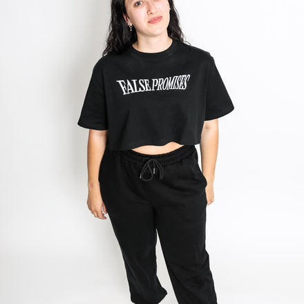 Loose-fitting black crop top made from 100% cotton, featuring the False Promises logo printed on the front.
